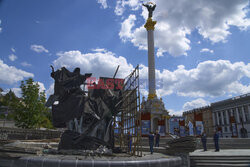 Municipal workers remove the cover that protected a monument of Kyiv