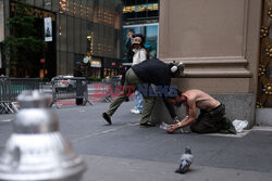 A homeless man begs for money as a woman takes a selfie