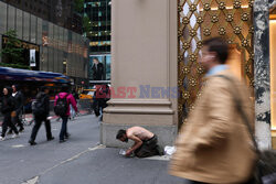 A homeless man begs for money as a woman takes a selfie